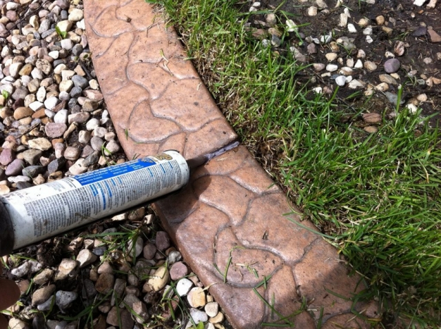 fill the gaps with caulking a shade darker than the curb